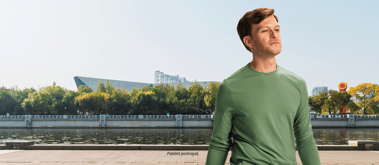 Man with rolling suitcase outdoors (patient portrayal)