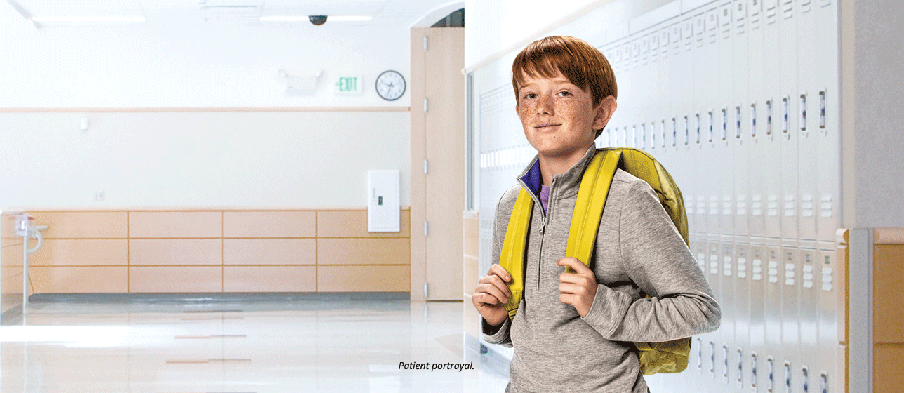 Boy with backpack in school (patient portrayal)