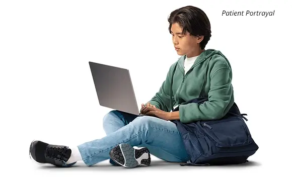 Teen sitting down using a laptop (patient portrayal)