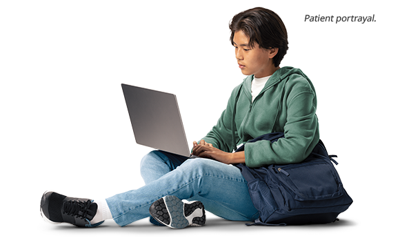 Teen sitting down using a laptop (patient portrayal)